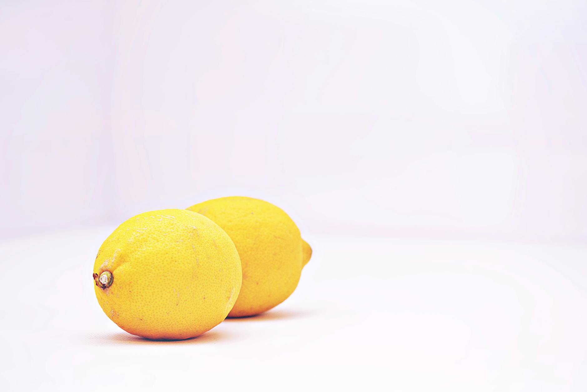 Two vibrant lemons on a minimalistic white background, symbolizing fresh sensation and simplicity