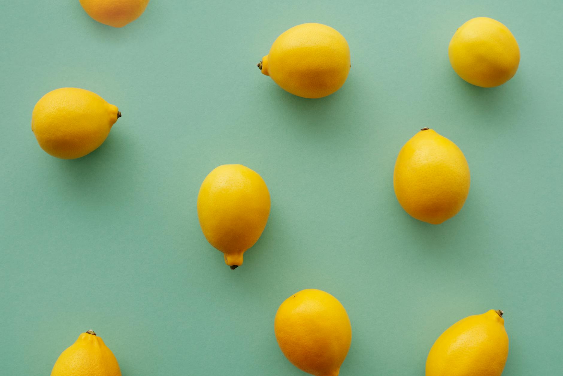 Bright yellow lemons arranged on a pastel green background, symbolizing the natural rhythm of the menstrual cycle and pleasure.