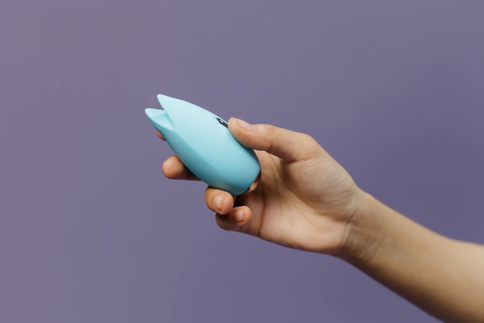 Blue silicone vibrator held in hand, demonstrating sensual self-care and pleasure.