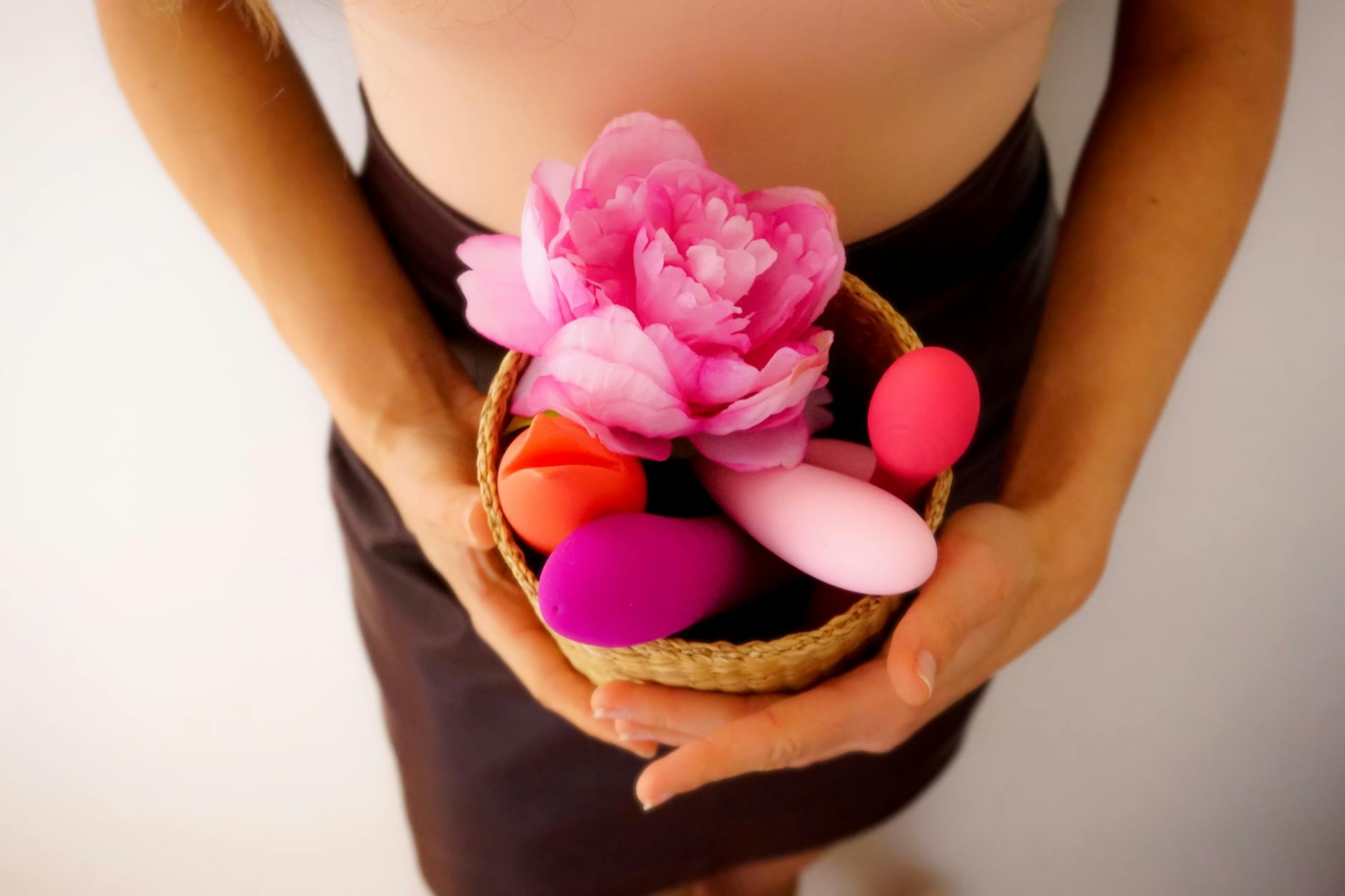 A person holding a pink clitoral vibrator in a calm, personal space