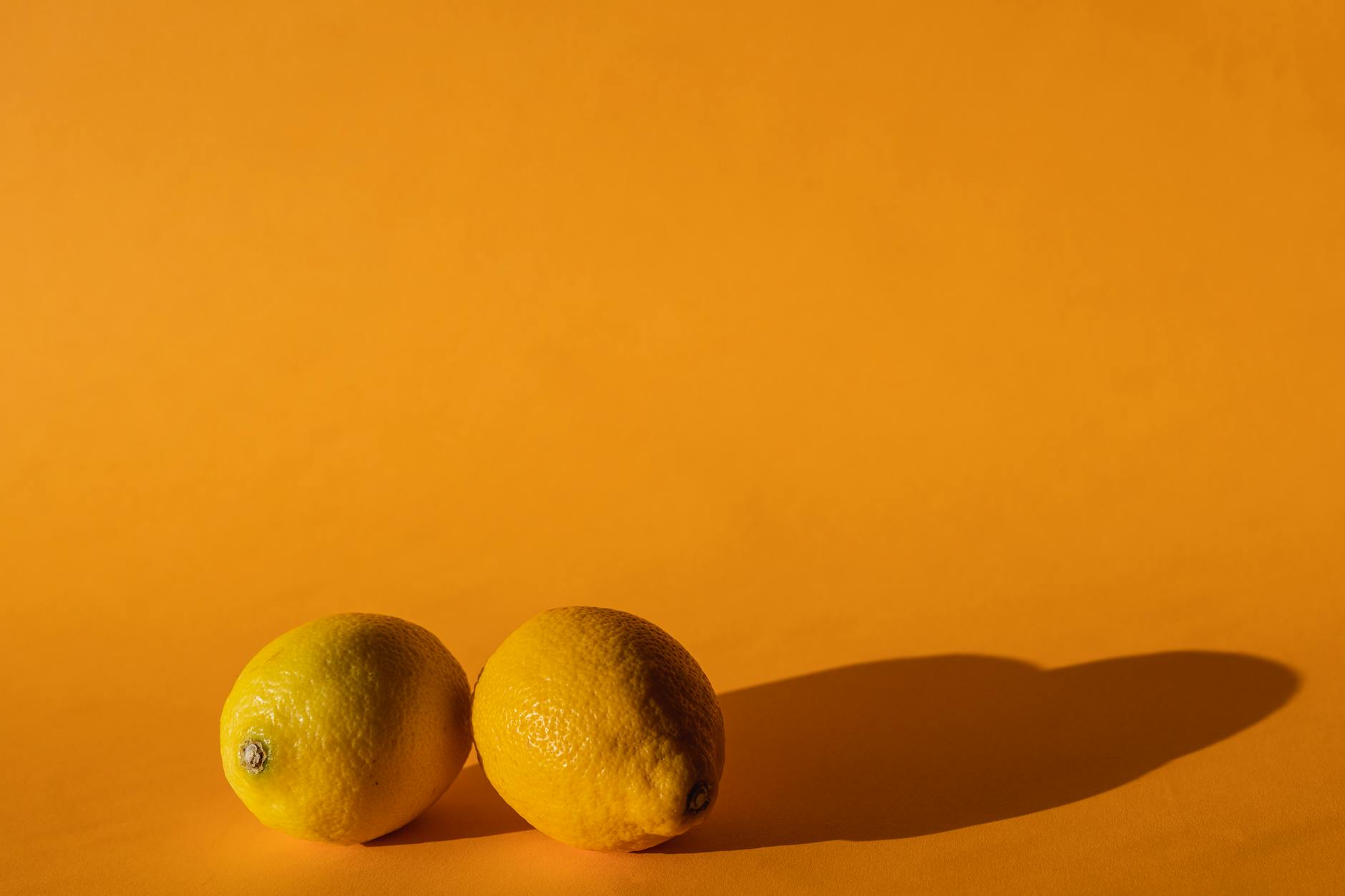Bright fresh lemons arranged on a yellow background in natural daylight